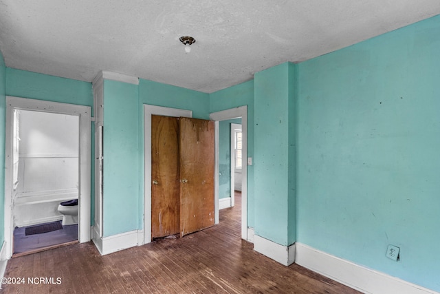 unfurnished bedroom featuring dark wood-type flooring and a textured ceiling