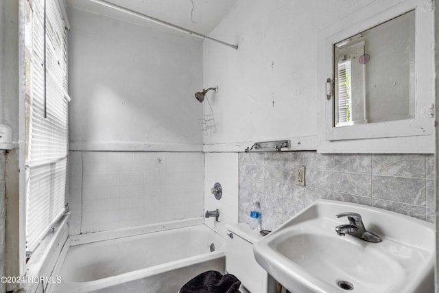 full bathroom featuring sink, bathing tub / shower combination, tile walls, and toilet