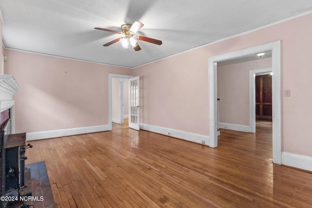 unfurnished living room featuring hardwood / wood-style floors, ceiling fan, crown molding, and a fireplace