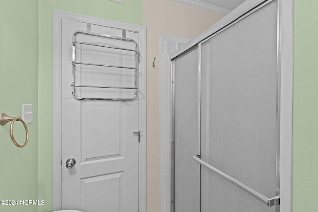 bathroom with ornamental molding and an enclosed shower