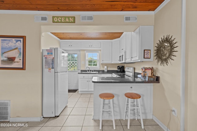 kitchen with white appliances, white cabinetry, a kitchen breakfast bar, ornamental molding, and kitchen peninsula