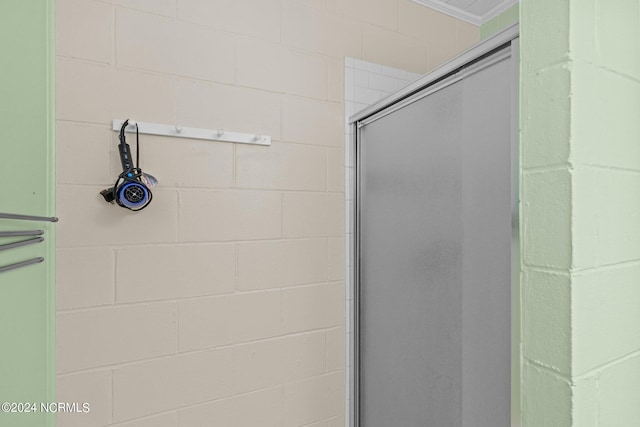 bathroom with a shower with door and crown molding