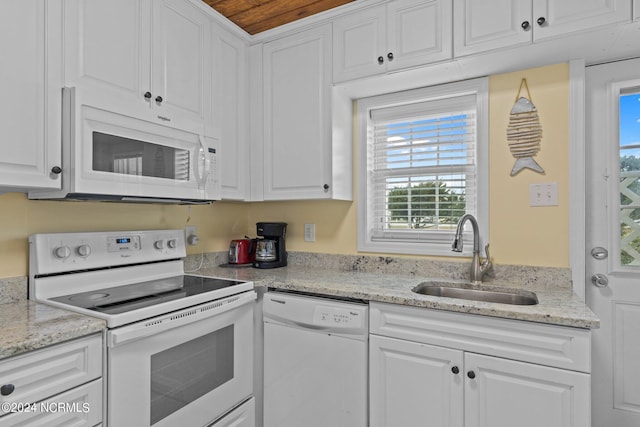 kitchen featuring light stone countertops, sink, white cabinets, and white appliances