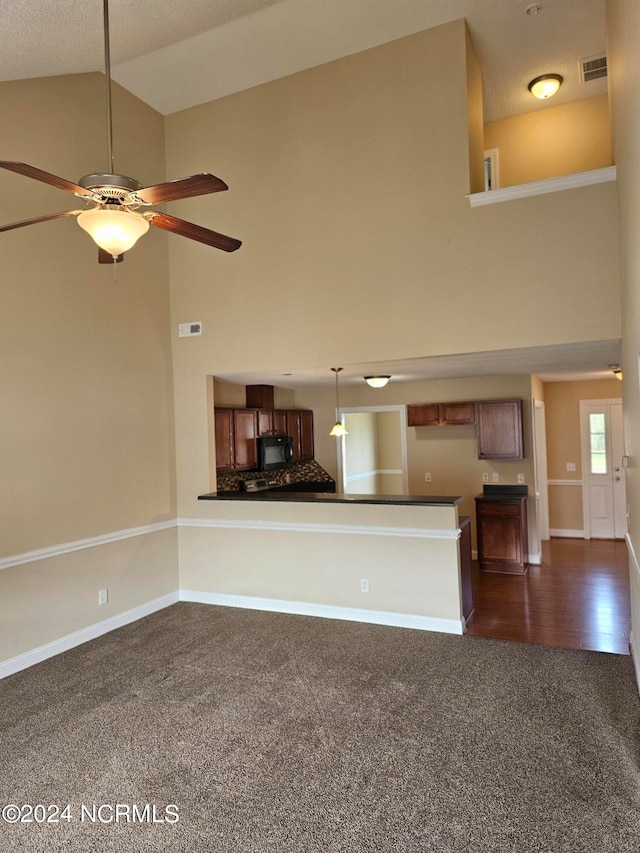 unfurnished living room featuring ceiling fan, high vaulted ceiling, and dark carpet