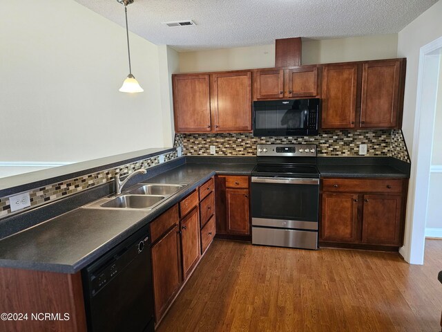 kitchen featuring black appliances, wood-type flooring, hanging light fixtures, sink, and backsplash