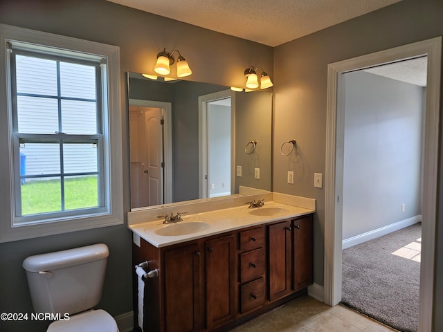 bathroom featuring a textured ceiling, toilet, and double sink vanity