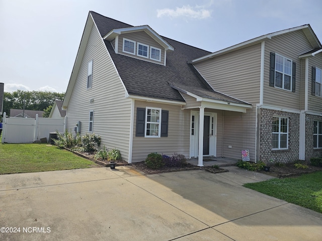 view of front of house with central AC unit, roof with shingles, a gate, fence, and a front lawn