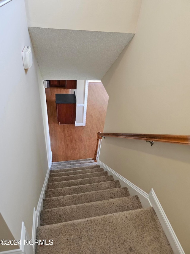 stairs with carpet flooring and a textured ceiling