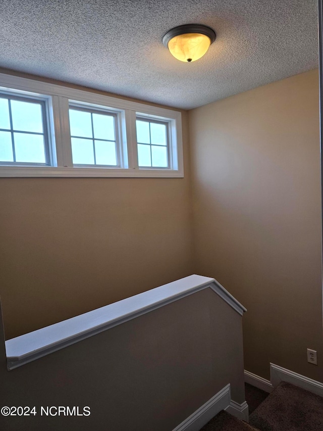 stairs with carpet floors and a textured ceiling