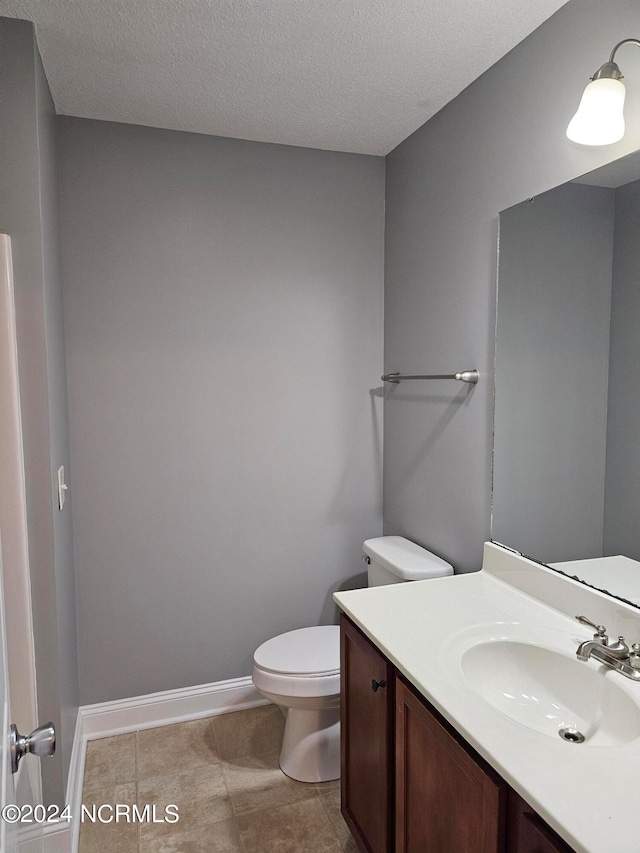 bathroom featuring vanity, toilet, a textured ceiling, and tile patterned flooring