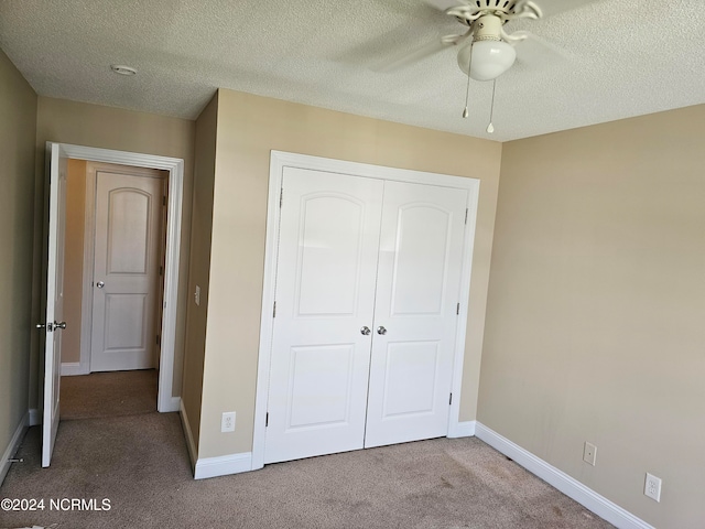 unfurnished bedroom featuring a textured ceiling, a closet, carpet floors, and ceiling fan