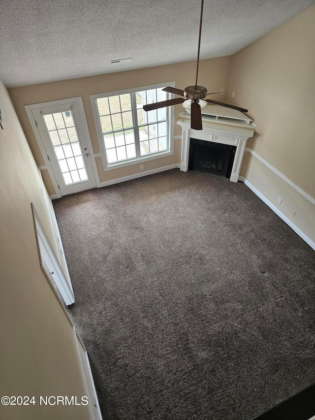 unfurnished living room with carpet flooring, a textured ceiling, and ceiling fan