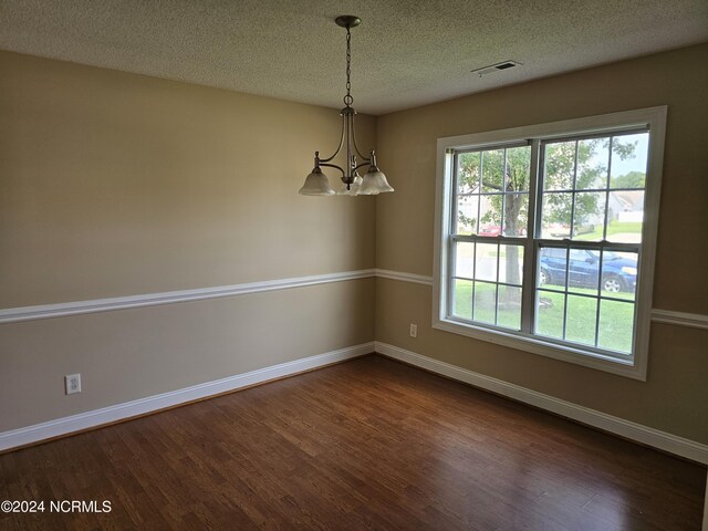 unfurnished room with dark hardwood / wood-style flooring, a chandelier, and a textured ceiling