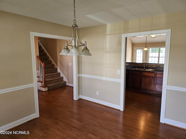 unfurnished dining area featuring sink, a textured ceiling, and dark hardwood / wood-style floors