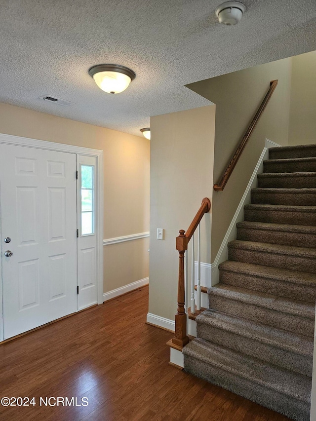 entryway with a textured ceiling and hardwood / wood-style flooring