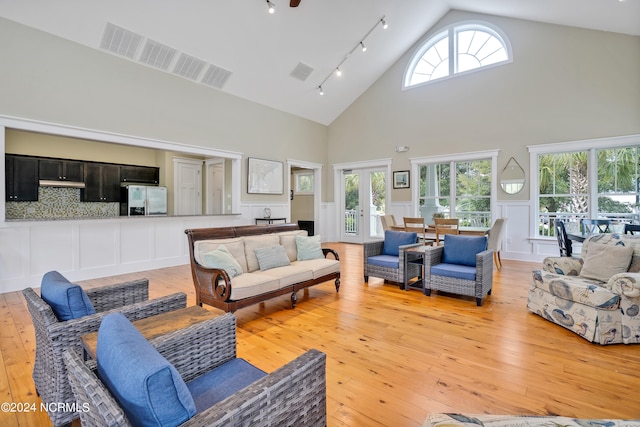 living room with light hardwood / wood-style floors, french doors, high vaulted ceiling, and track lighting