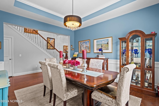 dining area with dark hardwood / wood-style floors, ornamental molding, a tray ceiling, and a chandelier