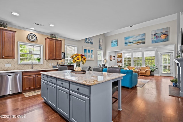 kitchen featuring a breakfast bar, dark wood-type flooring, stainless steel dishwasher, gray cabinets, and a kitchen island