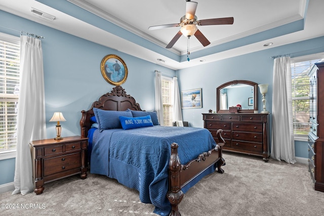 carpeted bedroom featuring a tray ceiling, ceiling fan, and crown molding