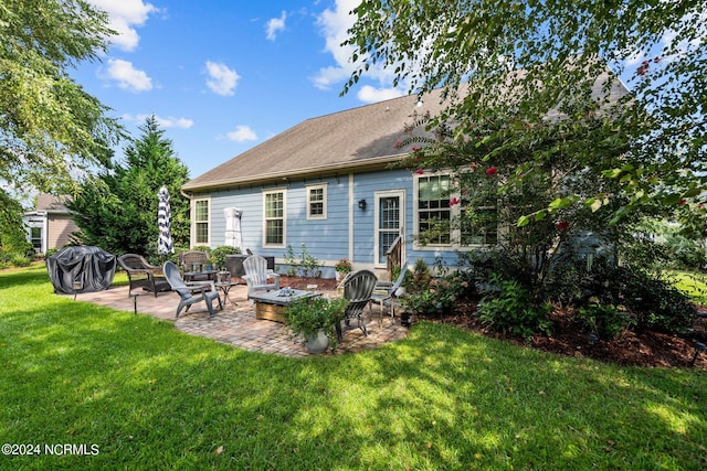 back of house featuring a lawn, a patio, and an outdoor fire pit