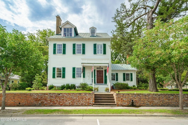 view of front of home with a standing seam roof, metal roof, and a chimney