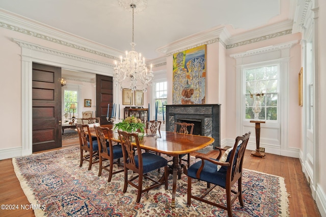 dining space with light hardwood / wood-style floors, crown molding, a premium fireplace, and a chandelier