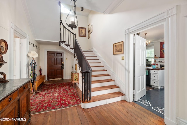 entrance foyer featuring crown molding, hardwood / wood-style floors, and a chandelier