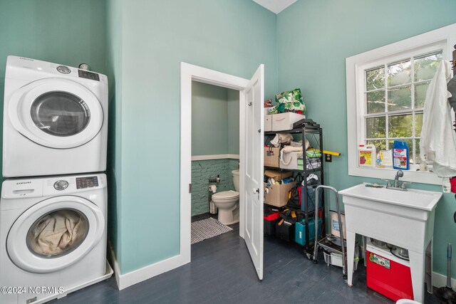 laundry room with dark hardwood / wood-style flooring and stacked washer / drying machine