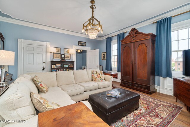 living room with an inviting chandelier, wood-type flooring, and ornamental molding