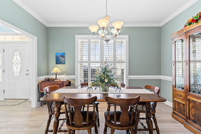 dining room with ornamental molding, an inviting chandelier, and light hardwood / wood-style flooring