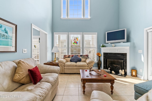 living room with light tile patterned flooring, a towering ceiling, a wealth of natural light, and a high end fireplace