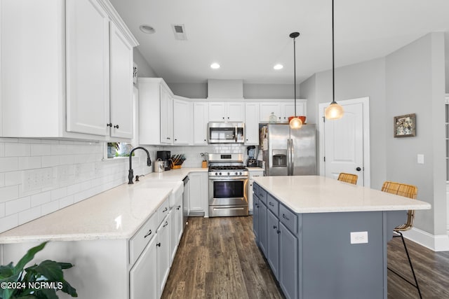 kitchen with a breakfast bar, a center island, white cabinets, dark hardwood / wood-style floors, and appliances with stainless steel finishes