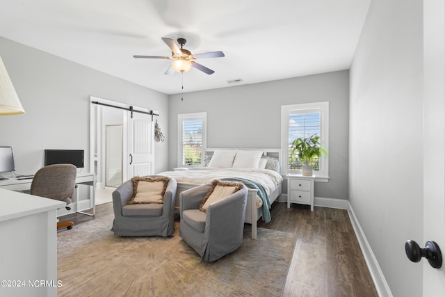 bedroom featuring wood-type flooring, a barn door, and ceiling fan