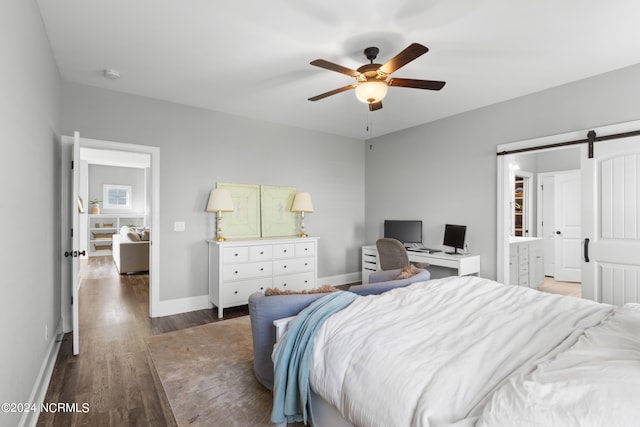 bedroom with ceiling fan, a barn door, and dark hardwood / wood-style flooring