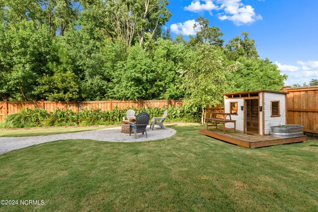 view of yard featuring a wooden deck, a patio, an outdoor structure, and an outdoor fire pit