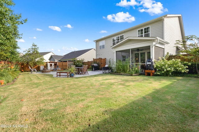 rear view of property with a sunroom, ceiling fan, a patio area, and a lawn