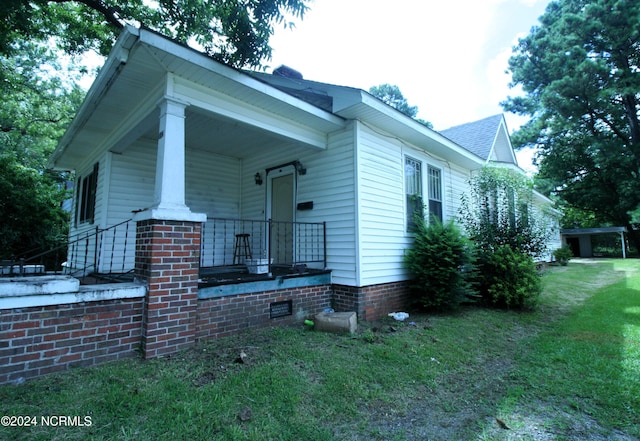 view of side of home with a yard and covered porch