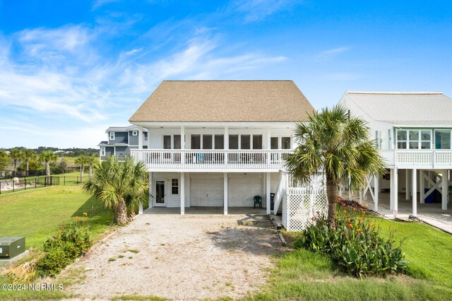 back of property featuring a garage, a balcony, and a yard