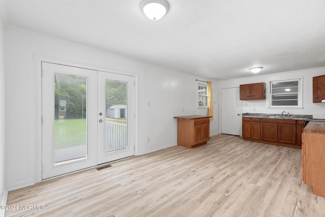 kitchen with light hardwood / wood-style floors, a textured ceiling, and french doors