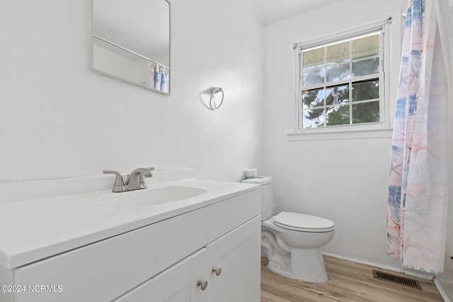 bathroom with hardwood / wood-style flooring, vanity, walk in shower, and toilet