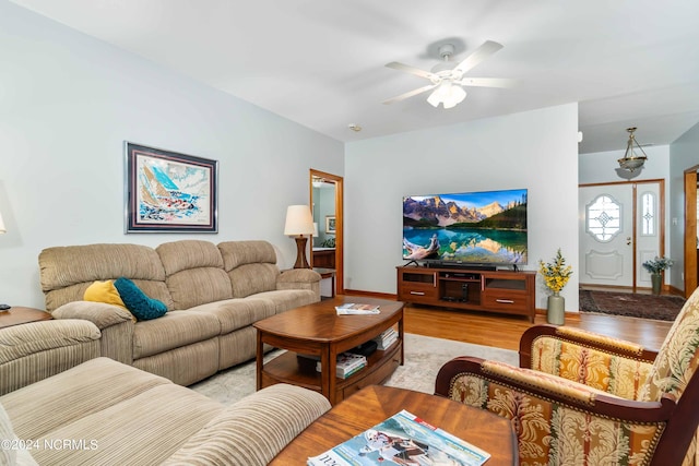 living room featuring baseboards, a ceiling fan, and light wood finished floors