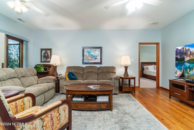 living room with baseboards, visible vents, light wood-style floors, and a ceiling fan