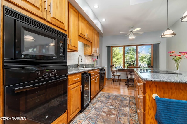 kitchen featuring light stone counters, black appliances, sink, wine cooler, and backsplash