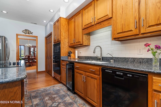 kitchen featuring an inviting chandelier, wine cooler, a sink, black appliances, and brown cabinets