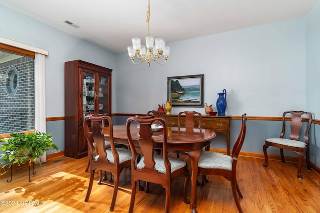 dining space featuring baseboards, visible vents, an inviting chandelier, and light wood finished floors
