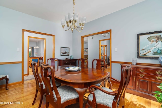 dining area with baseboards, light wood-style floors, and a notable chandelier
