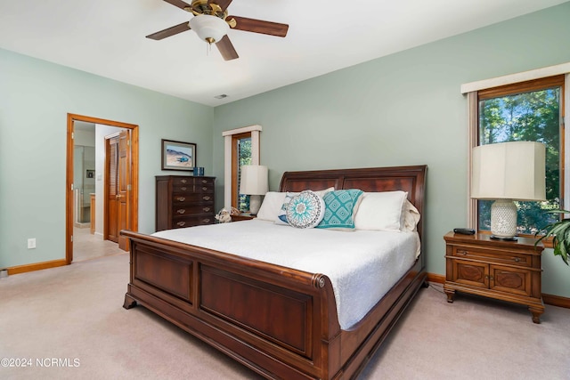 bedroom with light carpet, ensuite bathroom, baseboards, visible vents, and ceiling fan