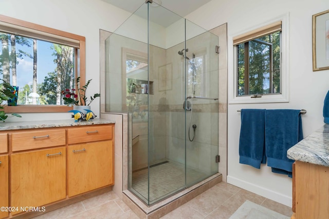 full bath with a stall shower, a wealth of natural light, tile patterned flooring, and vanity