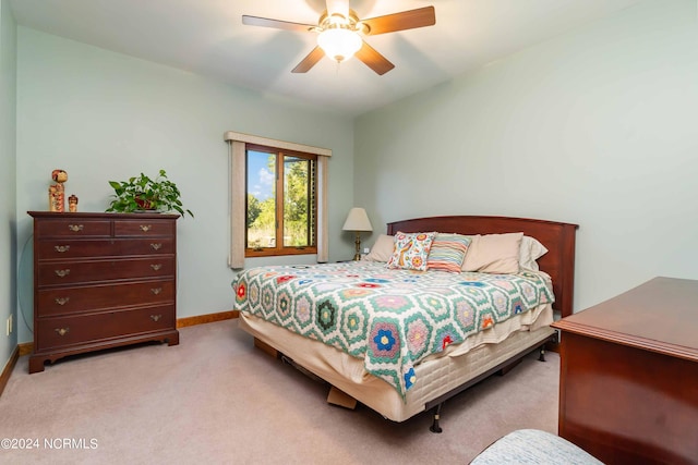 bedroom with light colored carpet, ceiling fan, and baseboards