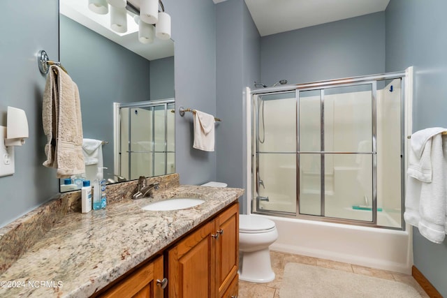 full bath with combined bath / shower with glass door, vanity, toilet, and tile patterned floors
